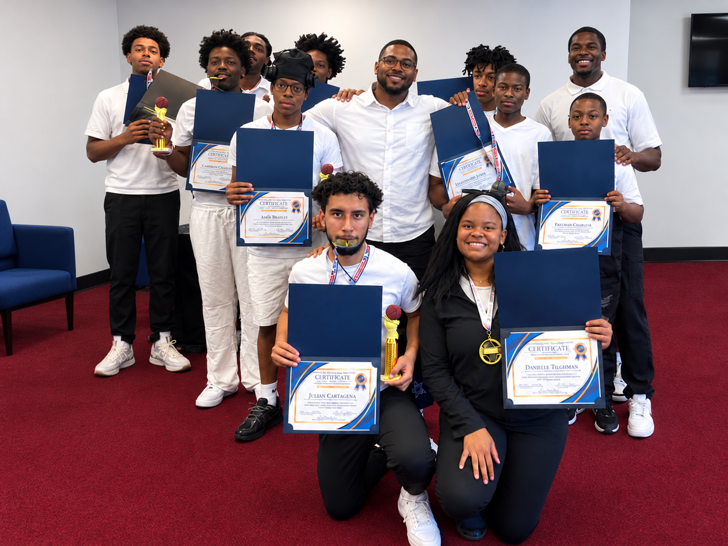 Program alumni and mentors holding their certificates and trophies together at an awards ceremony